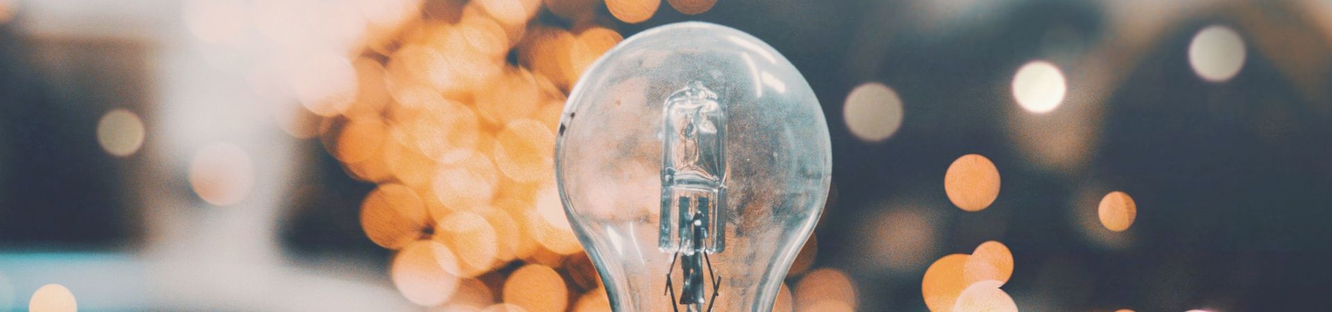 Hand holding a light bulb in front of a sparkling background