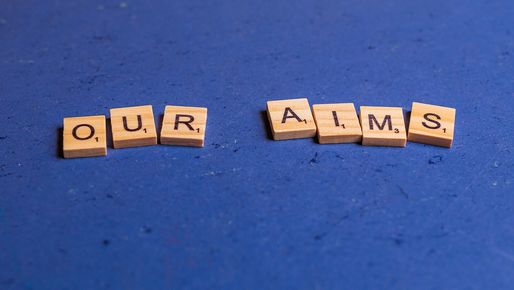 Alphabetic characters on small wooden blocks lying on a blue background, showing the words our aims