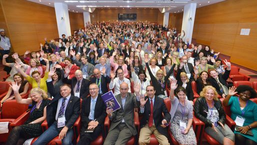 View in the room with a huge group of people raising their hand at a conference